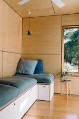 The living room is outfitted with a plush, built-in sofa with storage cubbies underneath. "It’s difficult to find ready-made pieces with storage that fit a unique space, so we built-in the desk, bed, and sofa," says Amy.