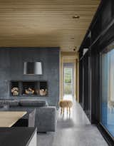 The minimalist material palette is picked up on the interiors as well, where a black concrete fireplace plays off the polished aggregate concrete floors. 