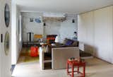 The row of storage continues into the living area. The sofa and ceramic coffee table are both from French designer Christophe Delcourt. The gray wall lamp is from Le Corbusier and the paper lantern is by Isamu Noguchi. 