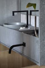 Rugged concrete stone by Caesarstone forms the bathroom counter and sinks, and hovers over the soaking tub.
