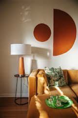 The velvet marigold sofa from Joybird is a favorite addition. "The ottomans aren't attached, so we can move them if my boyfriend and I don't want to sit next to each other, or we can make it a full bed," says Mamrie. The table lamp from Lamps Plus is the same Burnt Almond color as the mural.